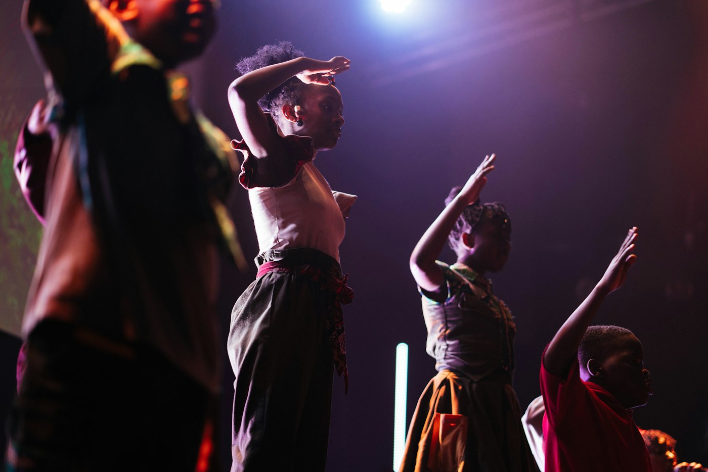 Young dancers raising their arms on a purple-lit stage